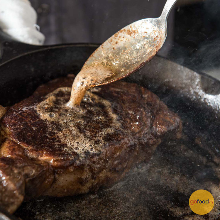 Nghiên chảo và rưới đều bơ lên miếng Steak
